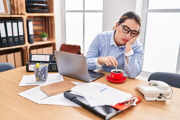 Young beautiful hispanic woman business worker tired drinking coffee at office