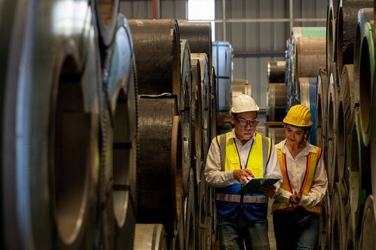 Warehouse inventory management in metalwork factory with engineer or inspector conduct storage check and quality control assessment on cylinder rolled metal for civil engineering project. Exemplifying