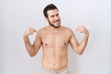 Fototapeta premium Young hispanic man standing shirtless over white background looking confident with smile on face, pointing oneself with fingers proud and happy.