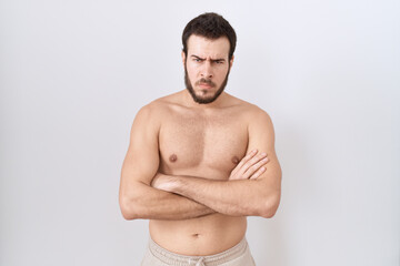 Young hispanic man standing shirtless over white background skeptic and nervous, disapproving expression on face with crossed arms. negative person.