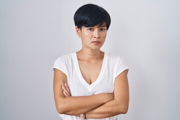 Young asian woman with short hair standing over isolated background skeptic and nervous,...