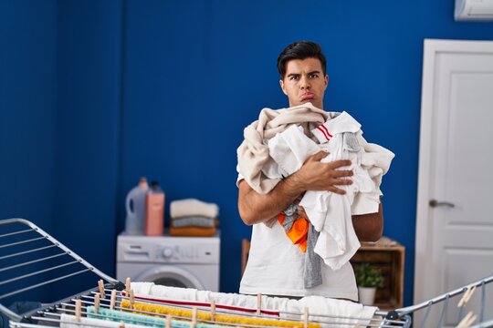 Hispanic man hanging clothes at clothesline depressed and worry for distress, crying angry and afraid. sad expression.