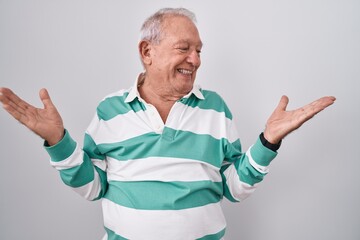 Senior man with grey hair standing over white background smiling showing both hands open palms, presenting and advertising comparison and balance