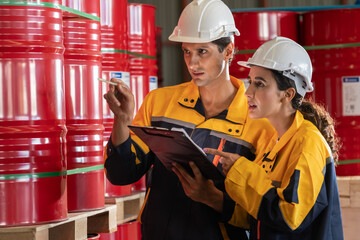 Two factory workers or inventory inspector conduct professional inspection on hazardous chemical barrels in warehouse, chemistry storage workplace and industrial profession concept. Exemplifying