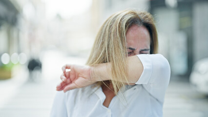 Middle age hispanic woman sneezing at street