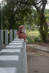A plush teddy bear sits on a concrete wall