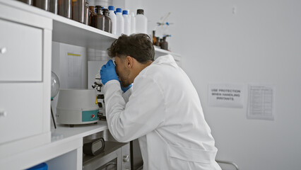 Young arab man scientist using microscope at laboratory