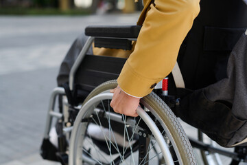 Obraz premium Close-up of young man with disability moving with wheelchair along the street