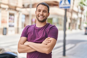 Young man smiling confident standing with arms crossed gesture at street