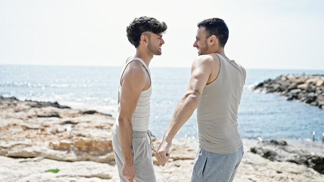 Two men couple smiling confident dancing at seaside