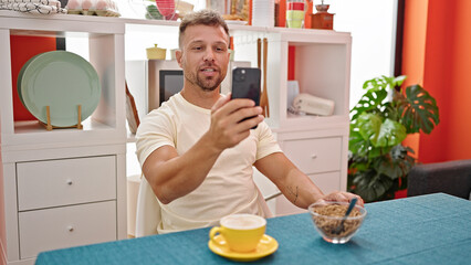 Young man having breakfast doing video call at dinning room