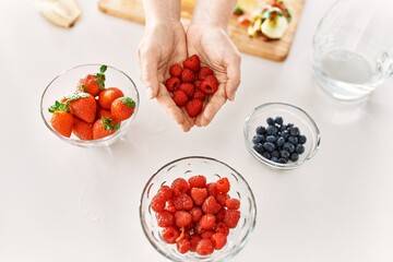 Young woman hoding raspberries at kitchen
