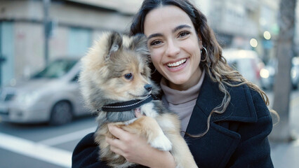 Young hispanic woman with dog smiling confident standing at street