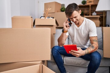 Young man talking on smartphone using credit card at new home