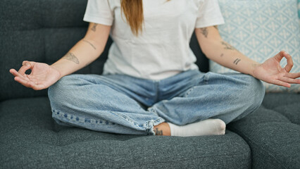Young beautiful hispanic woman doing yoga exercise sitting on sofa at home