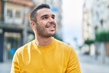 Fototapeta premium Young hispanic man smiling confident looking to the sky at street
