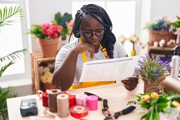 African american woman florist reading document with serious expression at florist