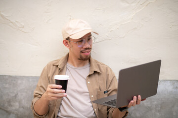 Freelance man relaxing with coffee while making video call on laptop.