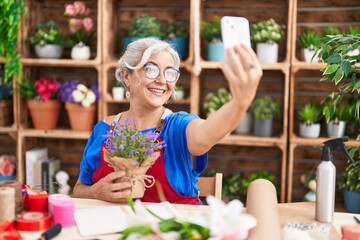 Middle age grey-haired woman florist make selfie by smartphone holding lavender plant at florist