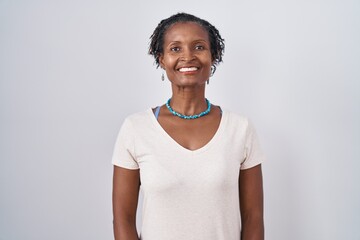 African woman with dreadlocks standing over white background with a happy and cool smile on face....