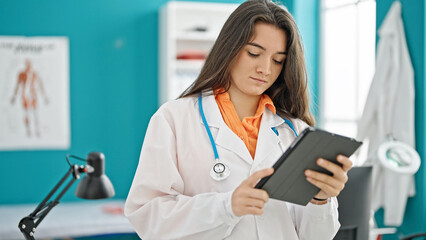 Young beautiful hispanic woman doctor using touchpad at clinic