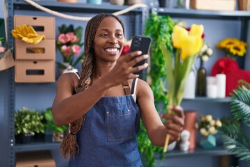 African american woman florist make photo to flower by smartphone at flower shop
