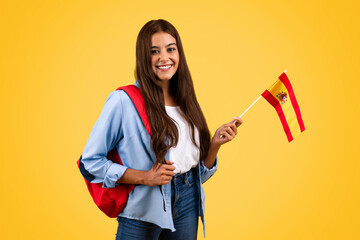 Happy european young student lady, with Spain flag, combines patriotism with education