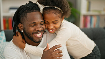 Obraz premium African american father and daughter smiling confident hugging each other sitting on sofa at home