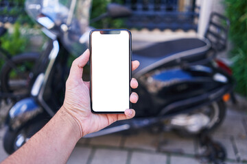 Man holding smartphone showing white blank screen at motorbike parking