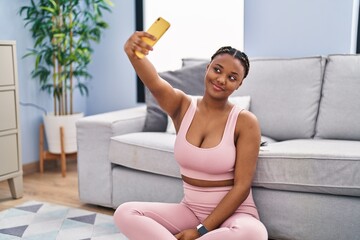 African american woman make selfie by smartphone sitting on floor at home