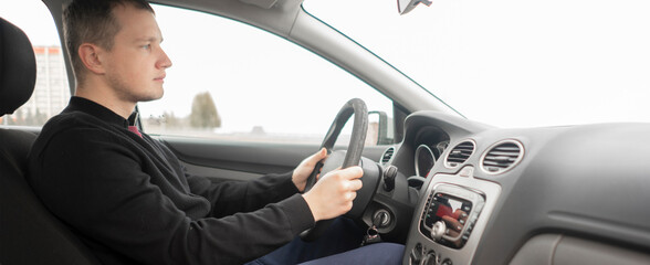 close up young male person driving a car, holding steering wheel, start the journey