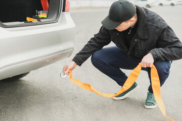 male driver attach the rope to a car's tow hook, car accident