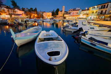 Marina with moored boats and promenade in the Croatian town of Malinska on the island of Krk in the evening