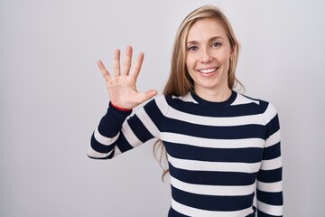 Young caucasian woman wearing casual navy sweater showing and pointing up with fingers number five while smiling confident and happy.