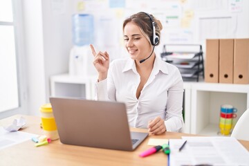 Obraz na płótnie Canvas Young blonde woman wearing call center agent headset smiling happy pointing with hand and finger to the side
