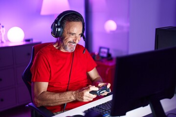 Middle age man streamer playing video game using joystick at gaming room