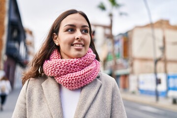 Young beautiful hispanic woman wearing scarf looking to the side at street