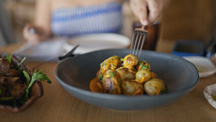 Young hispanic woman eating potatoes at the restaurant