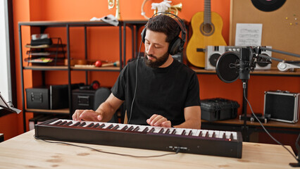 Young hispanic man musician playing piano at music studio