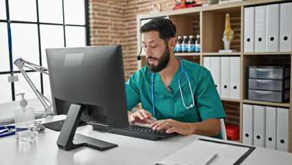 Young hispanic man doctor doing video call with computer at the clinic