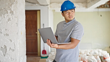  architect using laptop with serious expression at construction site