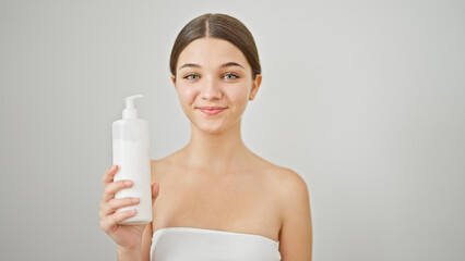 Young beautiful girl smiling confident holding cream bottle over isolated white background