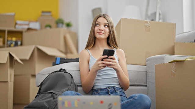 Young beautiful girl student using laptop and smartphone smiling at new home