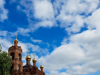 Domes of the church on the background of a blue sky with clouds