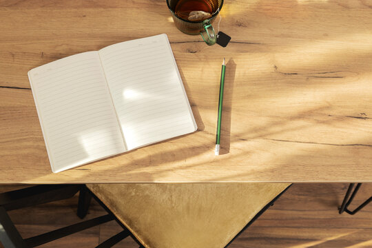 Concept of blank page, new beginning and mindfulness diary.Top view of table, chair, empty notebook, cup of tea. Warm and calm