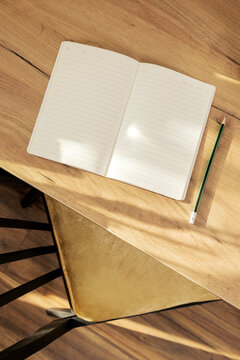 Vertical image of desk workplace. Empty blank page of notebook, pencil on the table. Natural calm and tranquil light, mood. Mindfulness diary process