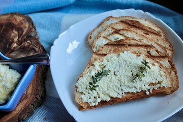 sandwiches from a loaf and with cheese paste on a wooden stand and in a white plate