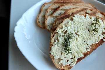 slice of bread, sandwiches from a loaf and with cheese paste on a wooden stand and in a white plate