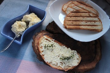 sandwiches from a loaf and with cheese paste on a wooden stand and in a white plate