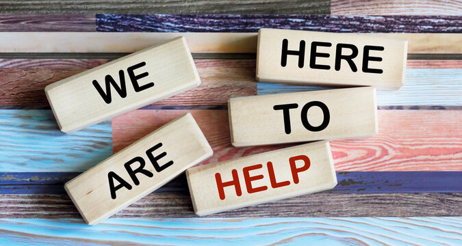Conceptual words we are here to help on wooden blocks. Beautiful background. Business and we are here to help the concept.